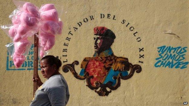 A cotton candy vendor stands next to a mural of Venezuela's late President Hugo Chavez on 22 March, 2014