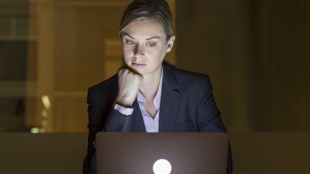 Woman looks at computer late at night