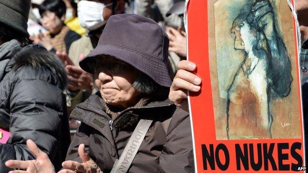 A demonstrator claps beside a 'No Nukes' poster during an anti-nuclear power plant rally in Tokyo on 15 March, 2014