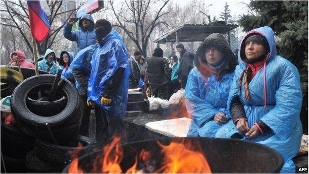 Pro-Russian activists warm themselves by a fire outside the Security Service building in the eastern Ukrainian city of Lugansk on 11/04/14