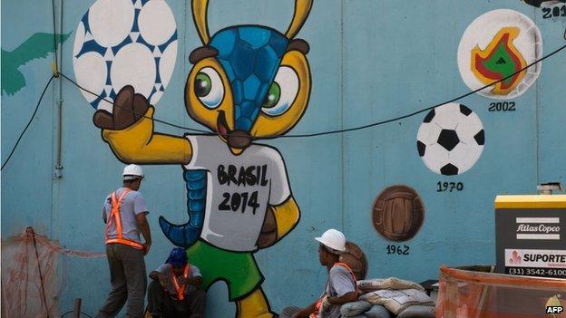 Workers rest next to a graffiti of Fuleco -the mascot of Brazil 2014 FIFA World Cup- near the Maracana metro in Rio de Janeiro on 8 April 2014.