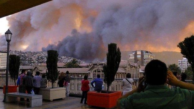 Locals in the centre of the city look on as the fire rages in the distance - 13 April 2014