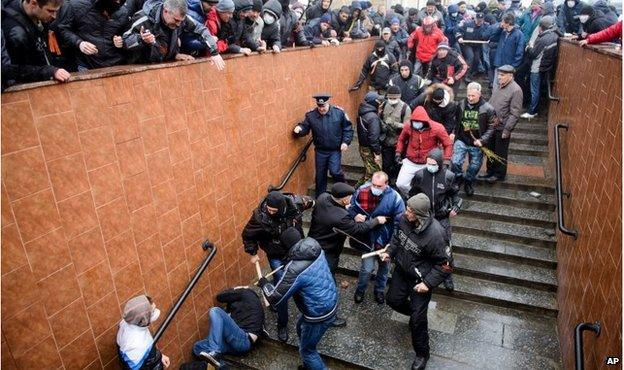 Pro-Russia supporters beat a pro-Western activist curled up on the ground, near a pro-Russia protest in Kharkiv