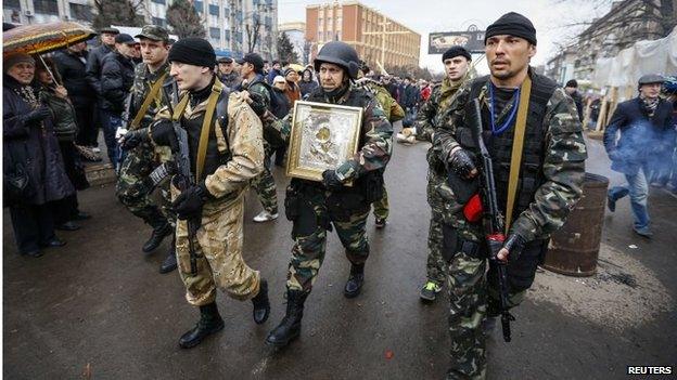 Armed pro-Russia protesters escort a comrade carrying an icon they said was found in the seized office of the state security service in Luhansk, which they handed over to the nearest Orthodox cathedral