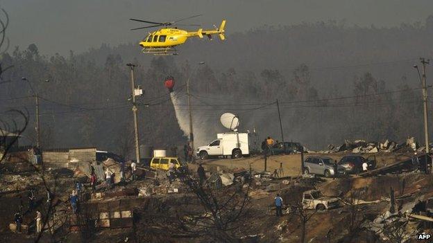 A helicopter empties a bucket of water to fight a fire in Valparaiso, on 14 April 2014