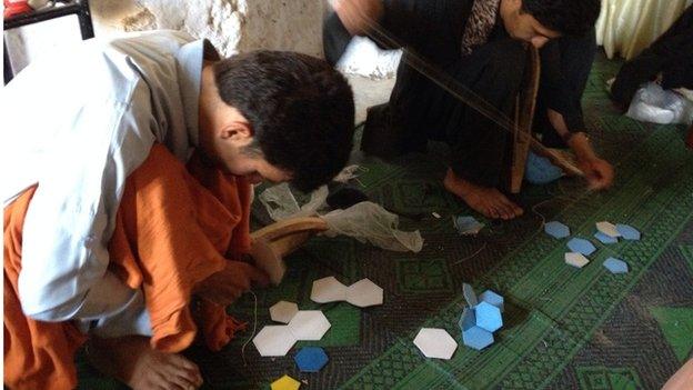 Young men stitch together footballs in South Waziristan