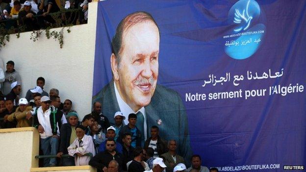 Supporters of Algerian President and presidential candidate Abdelaziz Bouteflika stand in front of his poster during a rally meeting in Annaba, east of Algiers