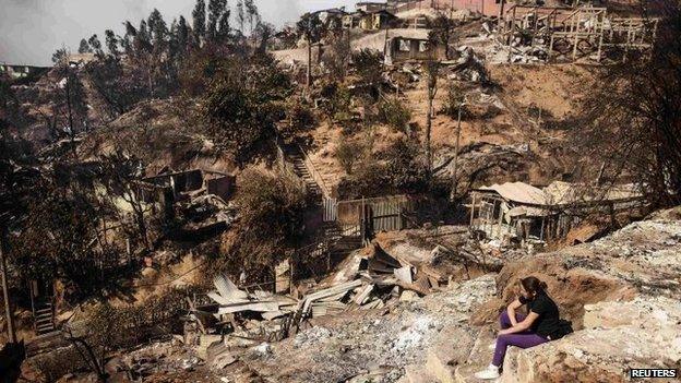 A resident whose home was destroyed by a major fire sits amid the destruction in Valparaiso on 13 April 2014