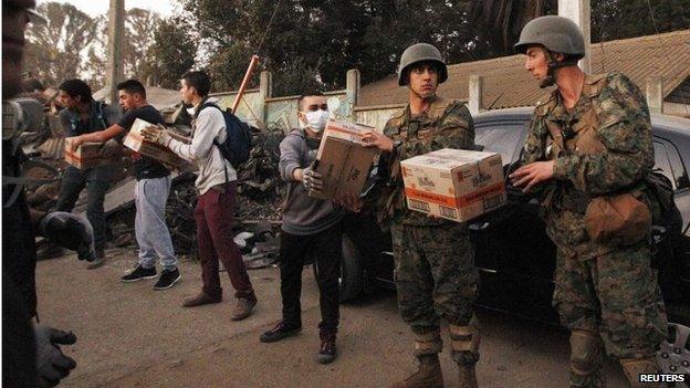 Soldiers deliver food supplies to affected residents after a fire burned several neighbourhoods on the hills in Valparaiso on 14 April 2014