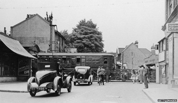 A Southern Electric train passes a level crossing in Mortlake, south-west London, 1937