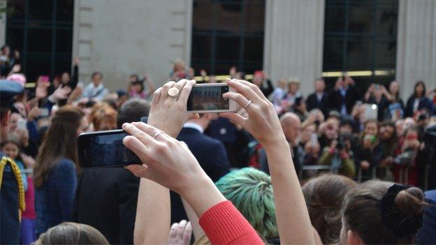 People try to take photos of the royals after the sun came out just in time for William and Kate to walk through Civic Square, before heading to Wellington Airport