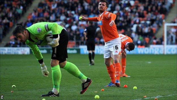 Blackpool caretaker player-manager Barry Ferguson clears tennis balls from the pitch