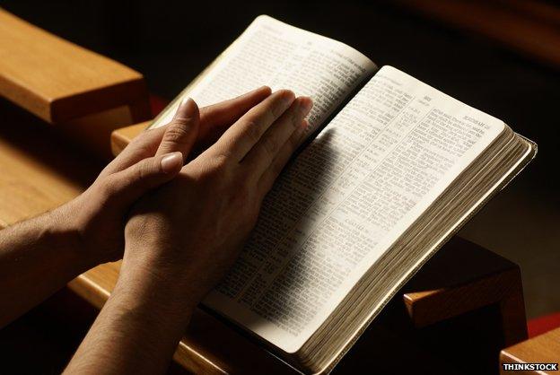 Hands in prayer over Bible