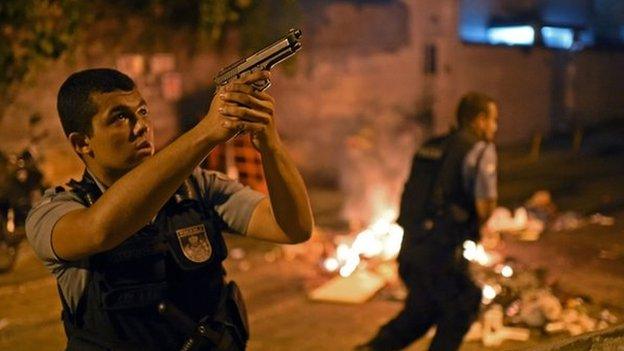 A Brazilian Police Special Forces member takes position during a violent protest in a favela near Copacabana in Rio de Janeiro, Brazil on 22 April 2014