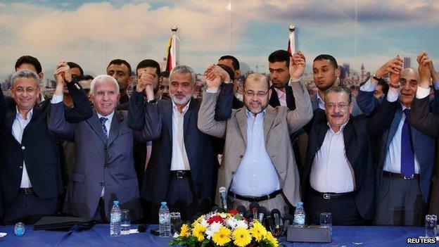 Members from Fatah and Hamas hold hands after announcing reconciliation deal in Gaza City on 23 April 2014