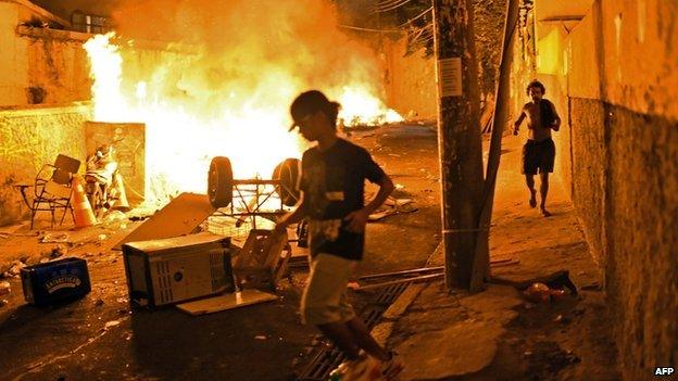 Residents run for cover during violent clashes between protestors and Brazilian Police Special Forces in a favela near Copacabana in Rio de Janeiro, Brazil on 22 April 2014.