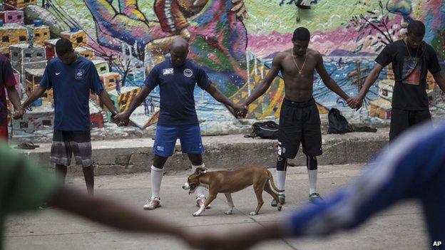 Friends and neighbours of the late Douglas Rafael da Silva Pereira pray in the Pavao Pavaozinho slum of Rio de Janeiro, Brazil, on 23 April 2014.