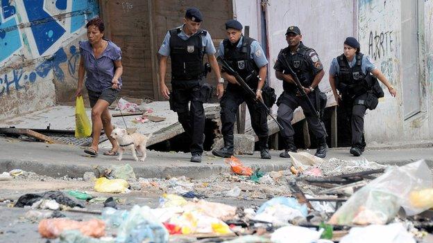 A group of militarized policemen walk in the streets of the Cantagalo favela where a young dancer was killed last weekend on 23 April 2014