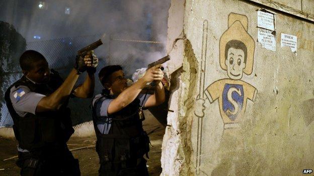 Brazilian policemen aim their guns during a violent protest in a favela next to Copacabana, Rio de Janeiro on 22 April 2014.