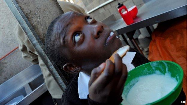 In this picture taken on May 17, 2012 a young boy who lost his parents to AIDS in Alexandra township in the north of Johannesburg enjoys a bowl of piping hot corn meal porridge (17 May 2012)