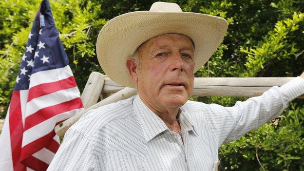 Nevada rancher Cliven Bundy stands in front of an American flag.