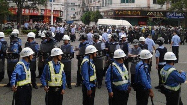 Policemen are seen on patrol as workers go on strike outside a Yue Yuen factory in Dongguan, Guangdong province, 15 April 2014