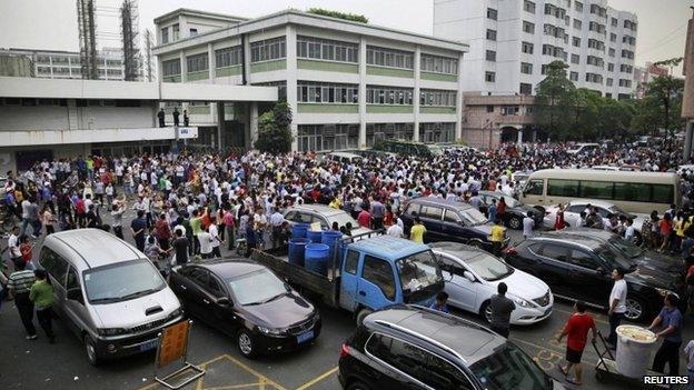 Workers protest during a strike as police stand guard at the factory area of Yue Yuen Industrial, in Dongguan, Guangdong province, 18 April 2014