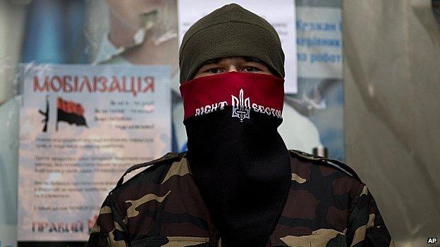 A masked man protects the entrance of a building transformed into a barracks in Kiev's Independence Square