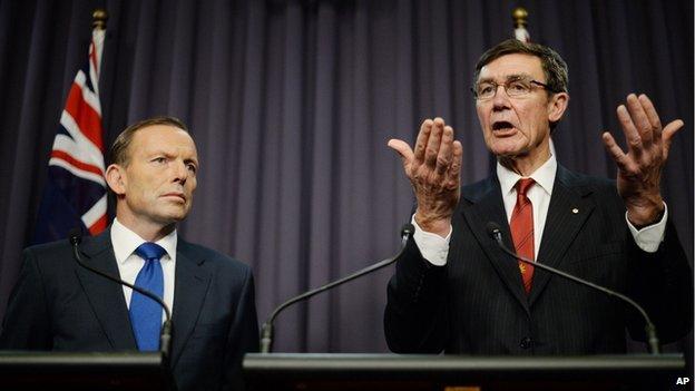 Prime Minister Tony Abbott looks on as retired Chief Air Marshall Angus Houston, the head of the Joint Agency Coordination Centre, speaks to the media during a press conference at Parliament House in Canberra, on Monday, 28 April, 2014