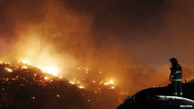 Firefighter work to put out a fire in Valparaiso city, northwest of Santiago on 13 April, 2014