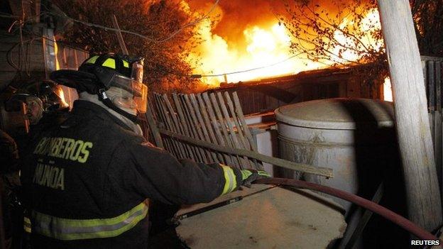 Firefighters work to put out a fire in Valparaiso city, northwest of Santiago on 13 April, 2014