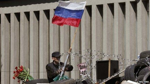 An activist attaches a Russian national flag on the barricades in front of the seized office of the SBU state security service in Luhansk, eastern Ukraine, April 28, 2014