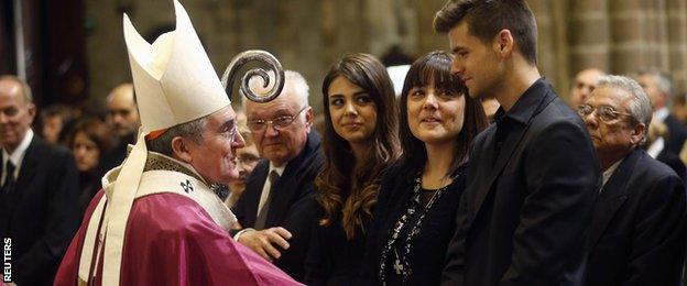 Archbishop Lluis Martinez Sistach (L) speaks to former Barcelona coach Tito Vilanova"s wife Montse (2nd R), son Adria