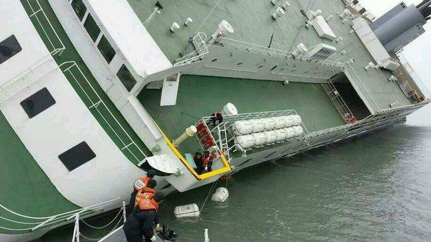 This South Korea Coast Guard handout photo taken at sea some 20 kilometres off the island of Byungpoong in Jindo on 16 April, 2014 shows South Korea Coast Guard members rescuing some of the passengers and crew aboard a South Korean ferry sinking on its way to Jeju island from Incheon