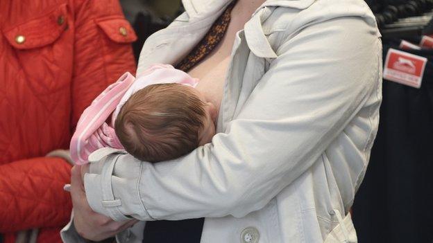 A mother breastfeeds her baby in Sports Direct