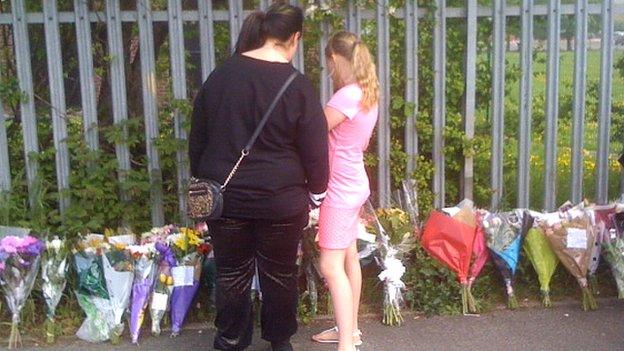 People looking at floral tributes