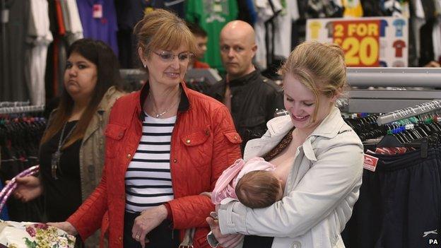 A mother breastfeeds her baby in Sports Direct