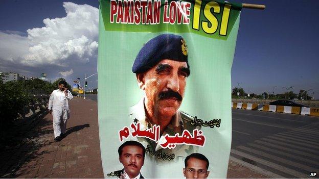 A man walks past a banner showing a picture of Pakistan"s Inter-Services Intelligence Chief Lt. General Zaheerul Islam, center, displayed by traders to show their support for the Pakistani army and ISI, in Islamabad, Pakistan, Saturday, April 26, 2014.