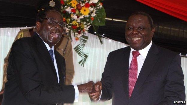 Zimbabwe President Robert Mugabe (L) jokes with Prime Minister Morgan Tsvangirai after signing Zimbabwe's new constitution into law, replacing a 33-year-old document forged in the dying days of British colonial rule and paving the way for elections, in Harare in this May 22, 2013 file photo.