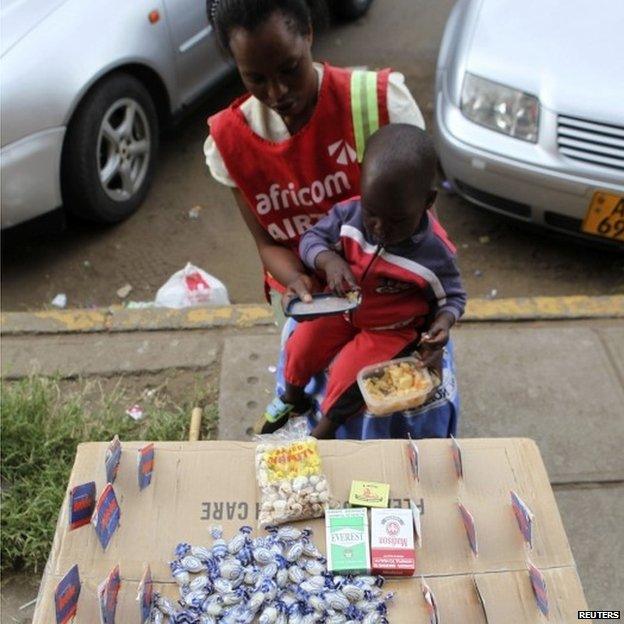 Thulisa Sibanda feeds her son as she waits for clients to buy mobile phone cards in central Harare, April 1, 2014.