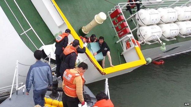 This screen grab taken from a video released by Korea Coast Guard on April 28, 2014 shows the sunken South Korean ferry "Sewol" captain Lee Joon-Seok (centre R), wearing a sweater and underpants, being rescued from the tilting vessel before it sank on April 16, 2014. South Korea"s coastguard on April 28 released a video showing the trouserless captain of a sinking ferry scrambling to safety as hundreds remained trapped inside - a move expected to intensify criticism of the crew over the disaster