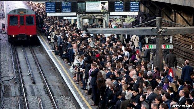 Commuters prepare to travel on the District Line of the London Underground which is running a limited service due to industrial action