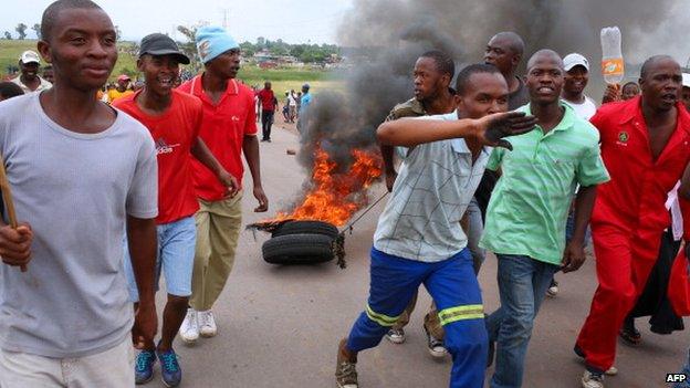 Protesting residents drag burning tyres as they march on the main road leading into the town of Bronkhorstspruit during a protest over poor public service delivery, on 6 February 2014