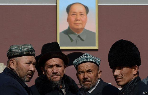 Uighurs pose for photos in front of a portrait of Mao Zedong in Beijing on March 3, 2013