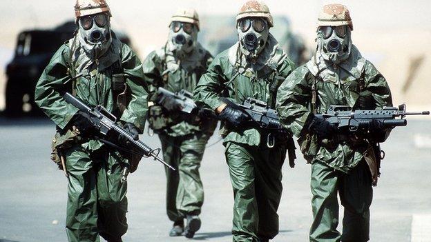 Soldiers walk around their camp wearing protective masks in this undated photo from during Operation Desert Shield