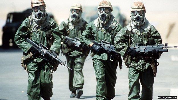 Soldiers walk around their camp wearing protective masks in this undated photo from during Operation Desert Shield