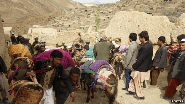 People walk with their belongings near the site of a landslide at Badakhshan province, 3 May 2014