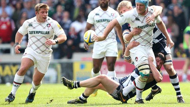 Leicester's Jordan Crane ooffloads in the tackle by Marc Jones and David Seymour of Sale