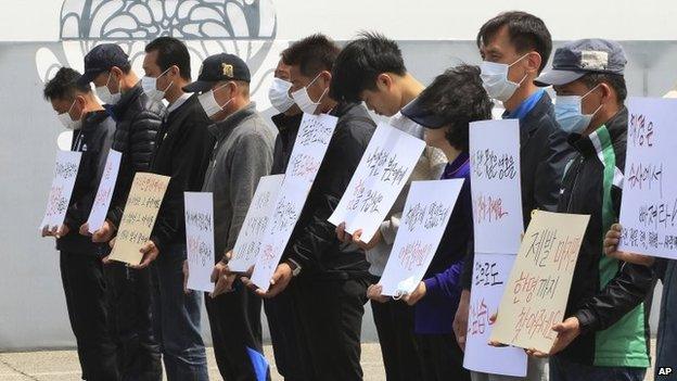 Family members of passengers aboard the sunken ferry Sewol stand to protest delays in the search operation at a group memorial altar in Ansan, South Korea, 4 May 2014