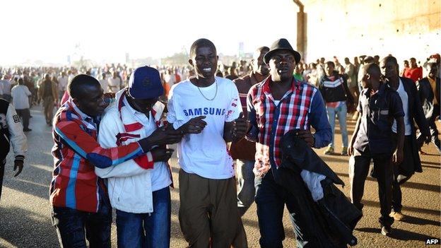 Injured men are being helped after two explosions hit two buses along Nairobi's Thika road, on 4 May 2014.